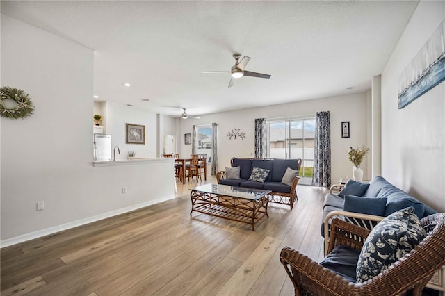 living room with light hardwood / wood-style floors, ceiling fan, and sink