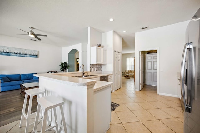 kitchen featuring a kitchen bar, ceiling fan, white cabinets, backsplash, and sink