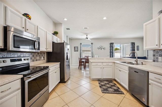 kitchen featuring ceiling fan, sink, white cabinets, stainless steel appliances, and tasteful backsplash