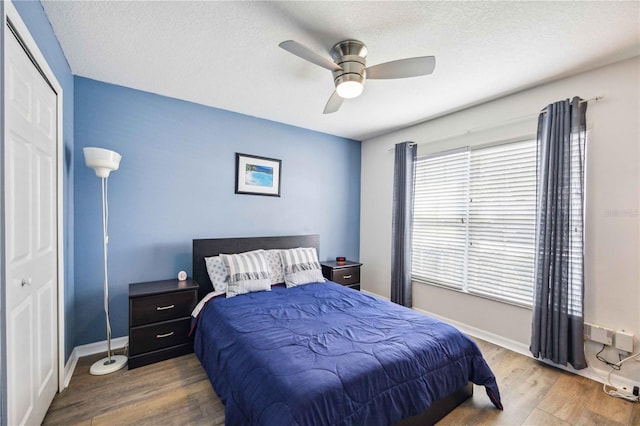 bedroom with a textured ceiling, a closet, ceiling fan, and hardwood / wood-style flooring