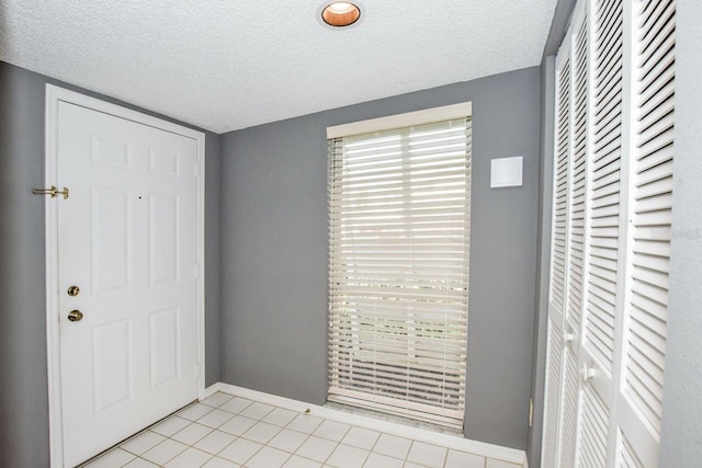 entryway featuring light tile patterned floors and a textured ceiling