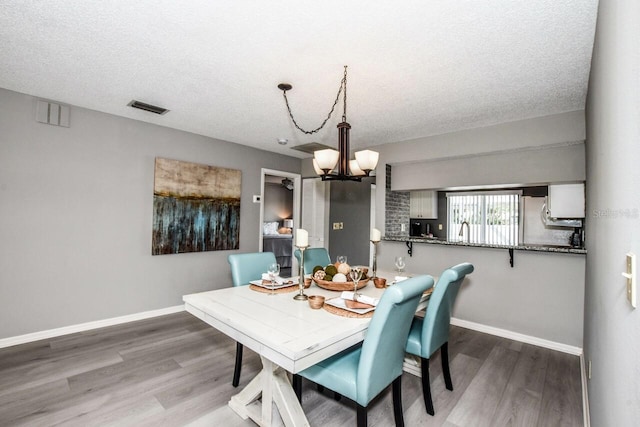 dining room with hardwood / wood-style floors, a notable chandelier, and a textured ceiling