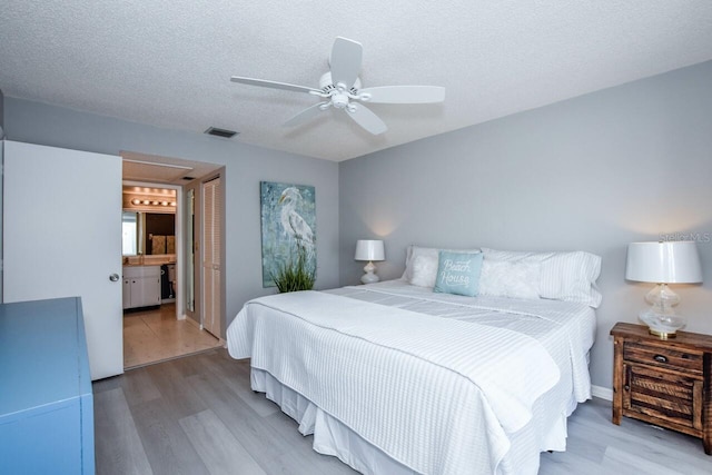 bedroom with ceiling fan, a textured ceiling, light wood-type flooring, and a closet