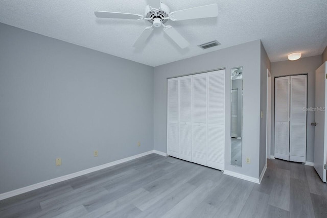 unfurnished bedroom with ceiling fan, a textured ceiling, and light wood-type flooring