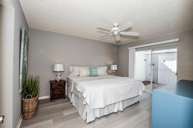 bedroom featuring access to exterior, light hardwood / wood-style floors, and a textured ceiling