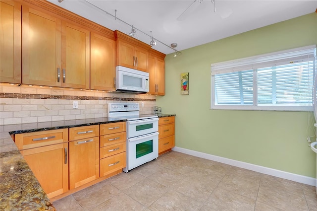 kitchen with white appliances, decorative backsplash, and dark stone counters