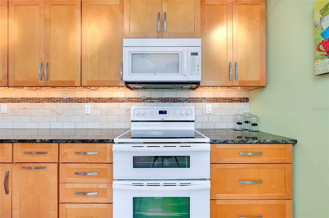 kitchen featuring white appliances, dark stone counters, and decorative backsplash