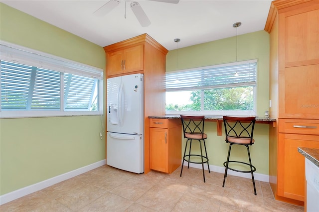 kitchen with a breakfast bar area, white fridge with ice dispenser, stone counters, pendant lighting, and ceiling fan