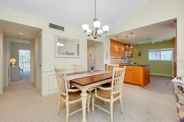 carpeted dining space featuring lofted ceiling, sink, and ceiling fan with notable chandelier