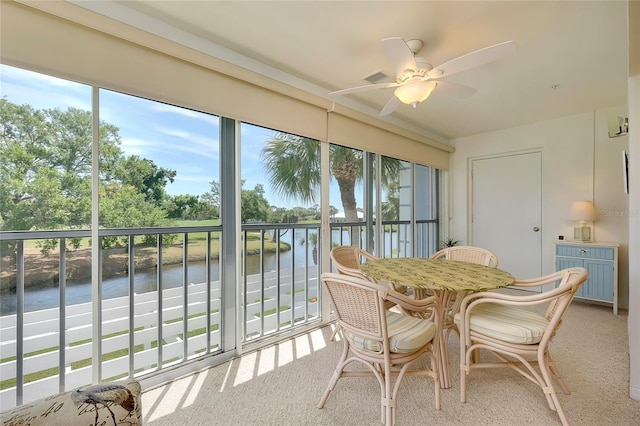 sunroom / solarium featuring ceiling fan and a water view