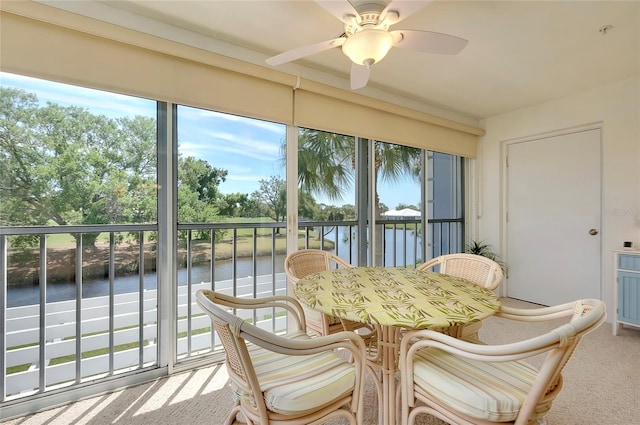 sunroom featuring a water view and ceiling fan