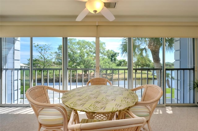 sunroom with a water view and ceiling fan