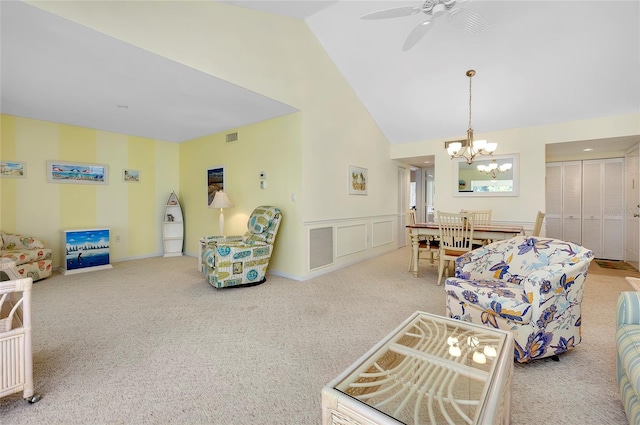 carpeted living room with ceiling fan with notable chandelier and high vaulted ceiling