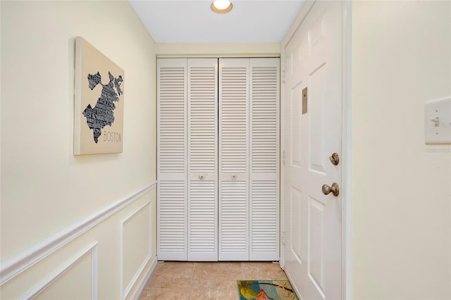 doorway featuring wainscoting and a decorative wall