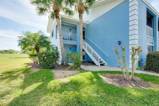 exterior space featuring stucco siding, stairway, and a yard