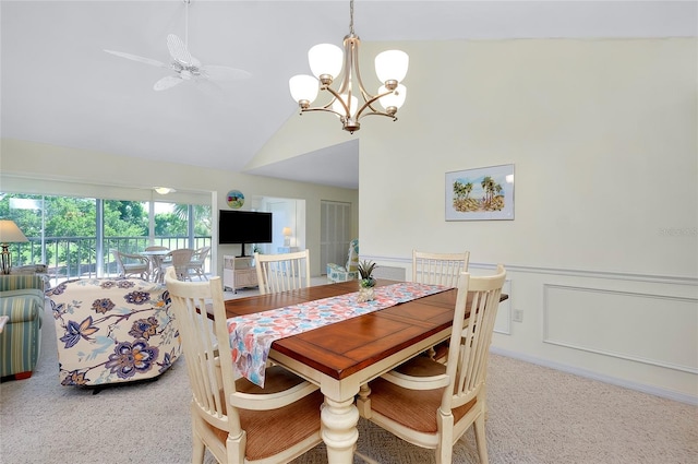 dining space with lofted ceiling, a decorative wall, a wainscoted wall, ceiling fan with notable chandelier, and carpet flooring