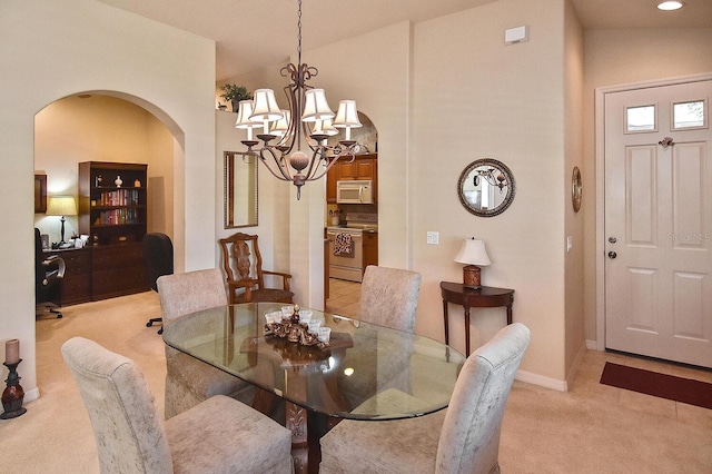 dining space featuring an inviting chandelier, lofted ceiling, and light carpet