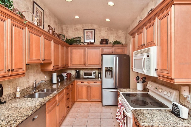 kitchen with white appliances, sink, light tile floors, light stone counters, and vaulted ceiling