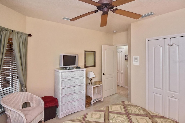 carpeted bedroom with ceiling fan and a closet