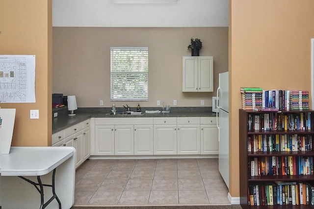 kitchen featuring light tile floors, white cabinetry, white fridge, and sink