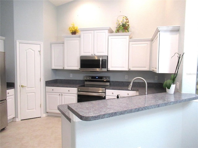 kitchen with kitchen peninsula, sink, stainless steel appliances, light tile flooring, and white cabinetry