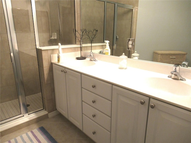 bathroom featuring a shower with shower door, double sink vanity, and tile flooring