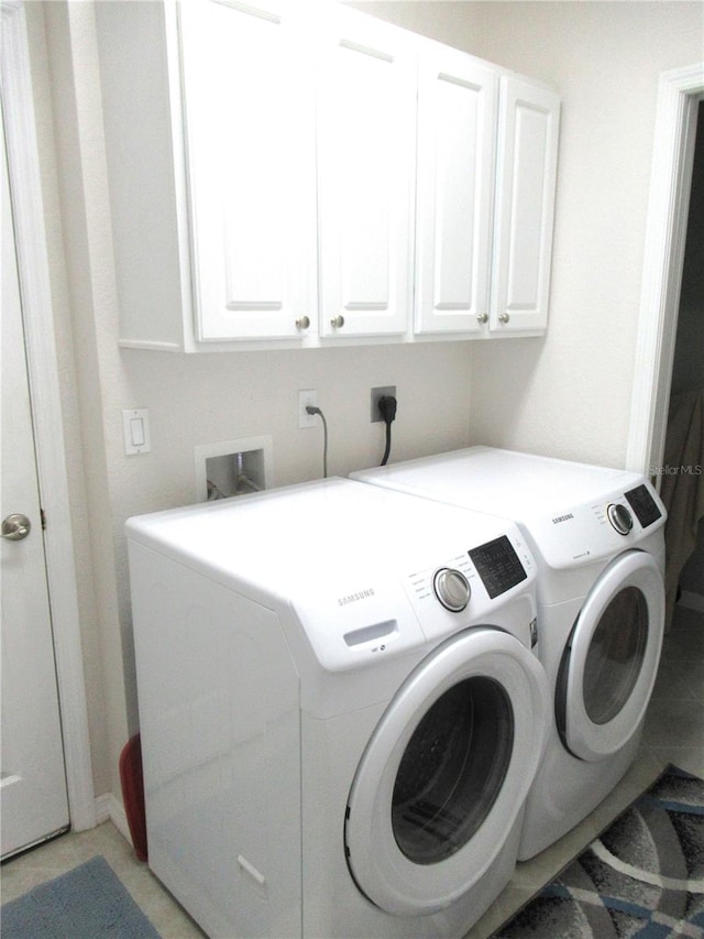 washroom with cabinets, light tile floors, electric dryer hookup, washer hookup, and washing machine and clothes dryer