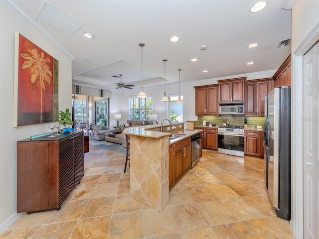 kitchen with decorative light fixtures, ceiling fan, appliances with stainless steel finishes, a breakfast bar, and sink