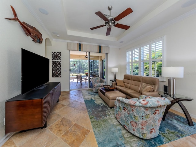 living room with a raised ceiling, crown molding, ceiling fan, and light tile floors