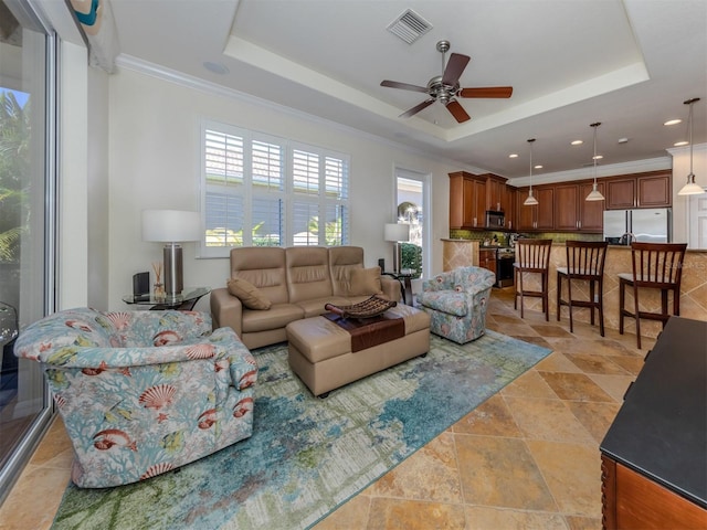 tiled living room with a raised ceiling, crown molding, and ceiling fan