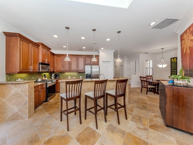 kitchen with backsplash, a kitchen breakfast bar, hanging light fixtures, and stainless steel appliances