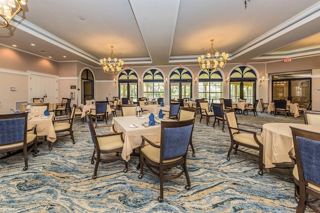 carpeted dining space with a raised ceiling, an inviting chandelier, and ornamental molding