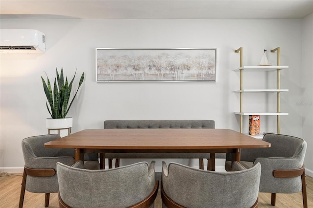 dining room with a wall mounted AC and light hardwood / wood-style flooring