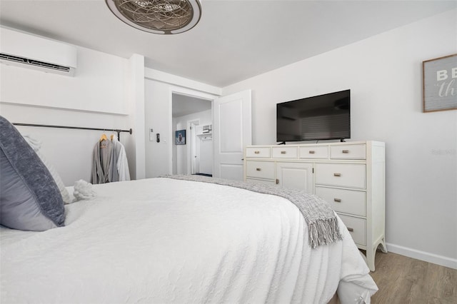 bedroom featuring light hardwood / wood-style flooring and a wall unit AC