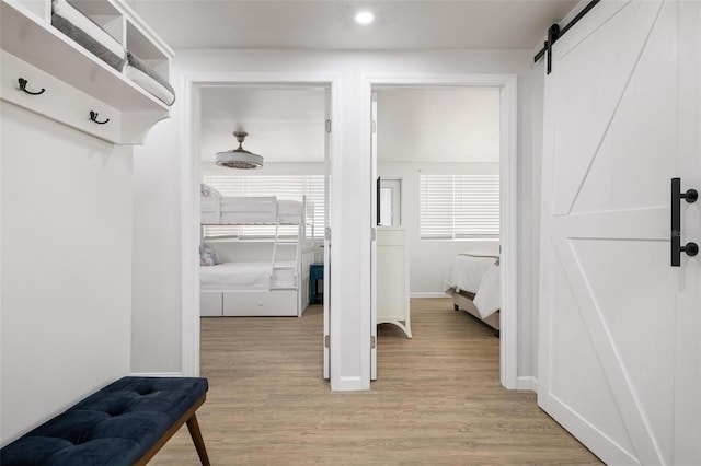 corridor with a barn door and light wood-type flooring