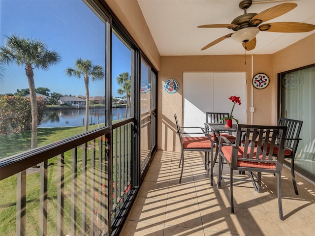 sunroom / solarium featuring a water view and ceiling fan