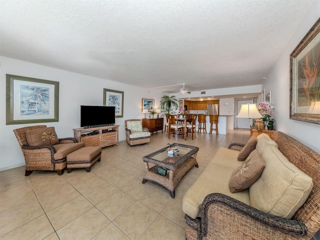 living room with a textured ceiling, ceiling fan, and light tile patterned flooring