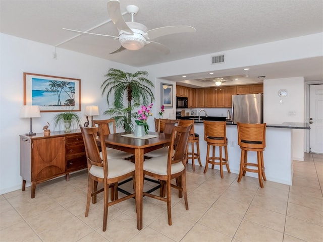 dining space featuring ceiling fan, sink, light tile patterned floors, and a textured ceiling