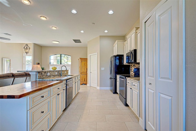 kitchen featuring a kitchen island with sink, sink, light tile floors, light stone counters, and stainless steel appliances