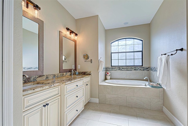 bathroom featuring tiled tub, dual vanity, and tile flooring