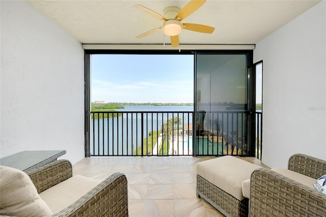 sunroom / solarium featuring a water view and ceiling fan