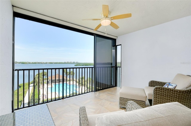 balcony with ceiling fan and a water view