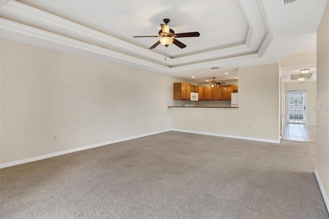 unfurnished living room with light carpet, a tray ceiling, and ceiling fan