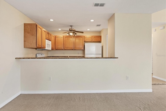 kitchen with white appliances, dark stone countertops, ceiling fan, and light colored carpet