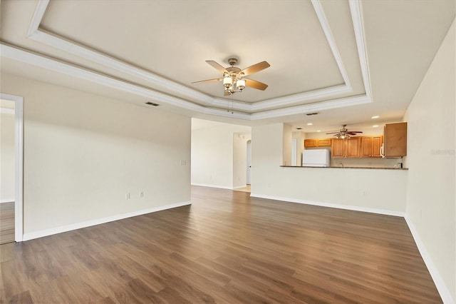 unfurnished living room featuring a raised ceiling, dark hardwood / wood-style floors, crown molding, and ceiling fan