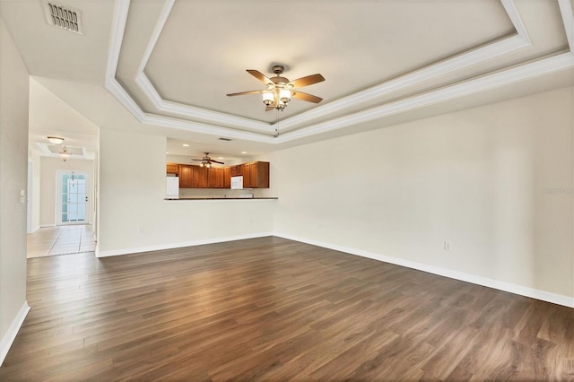 unfurnished living room featuring a raised ceiling, ceiling fan, and dark hardwood / wood-style flooring