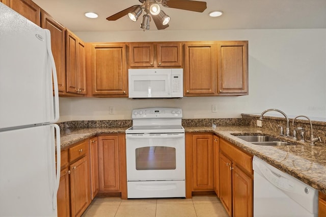 kitchen featuring light tile flooring, ceiling fan, white appliances, dark stone countertops, and sink