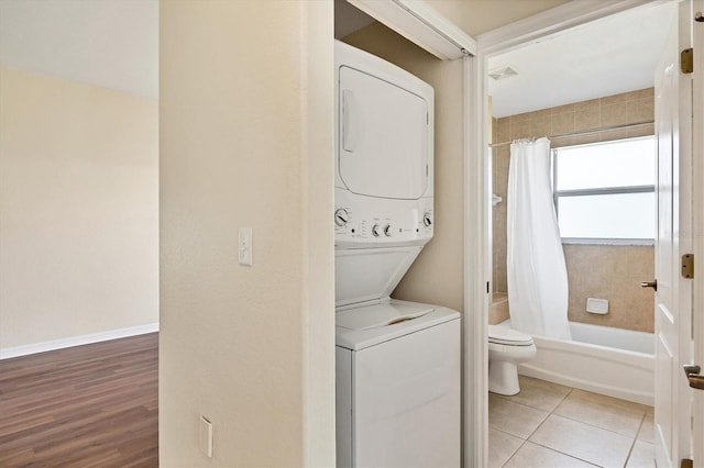 laundry area with stacked washing maching and dryer and light tile floors