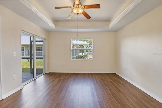 empty room with a raised ceiling, crown molding, ceiling fan, and dark hardwood / wood-style flooring