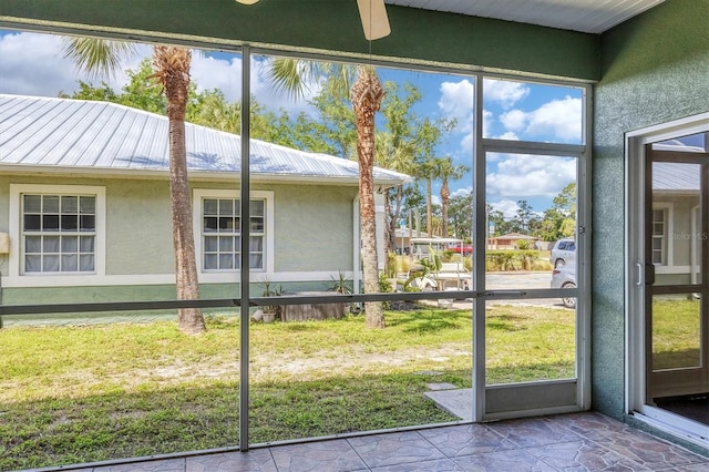 doorway featuring ceiling fan and dark tile flooring